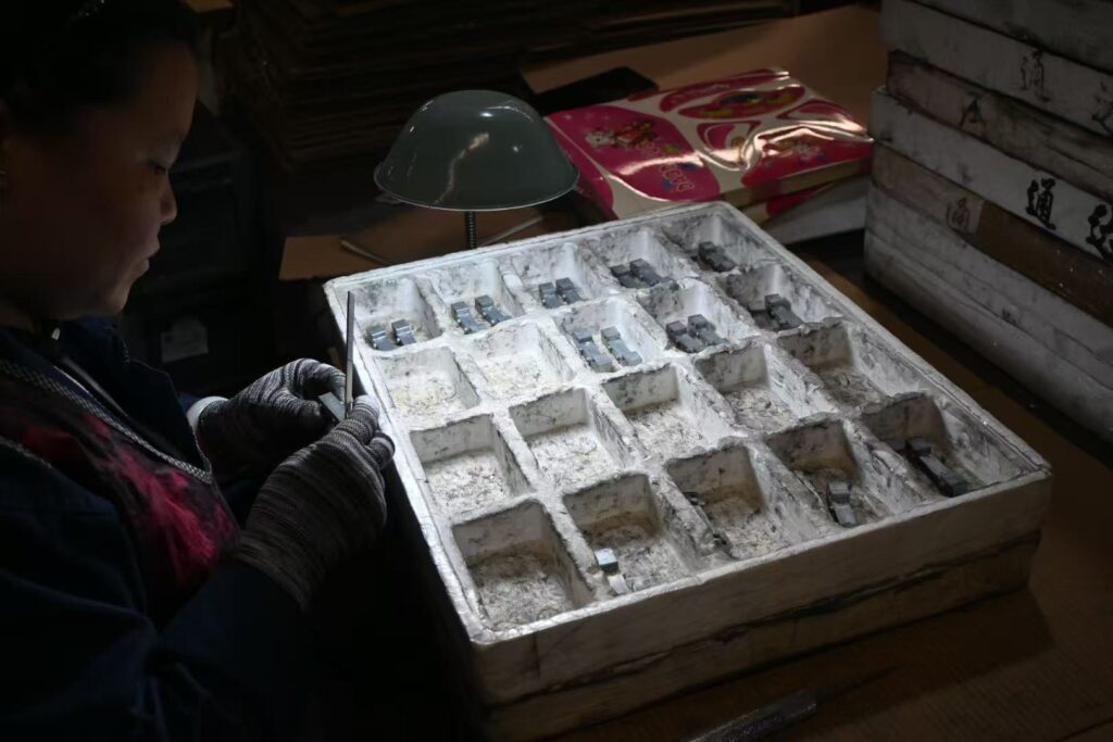 Manual visual inspection and careful packaging of small precision die-cast parts into foam trays at Sureton.